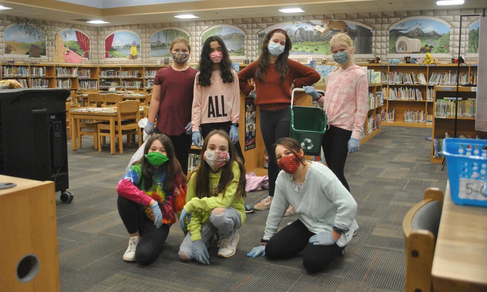 Seven girls pose for a picture in a library